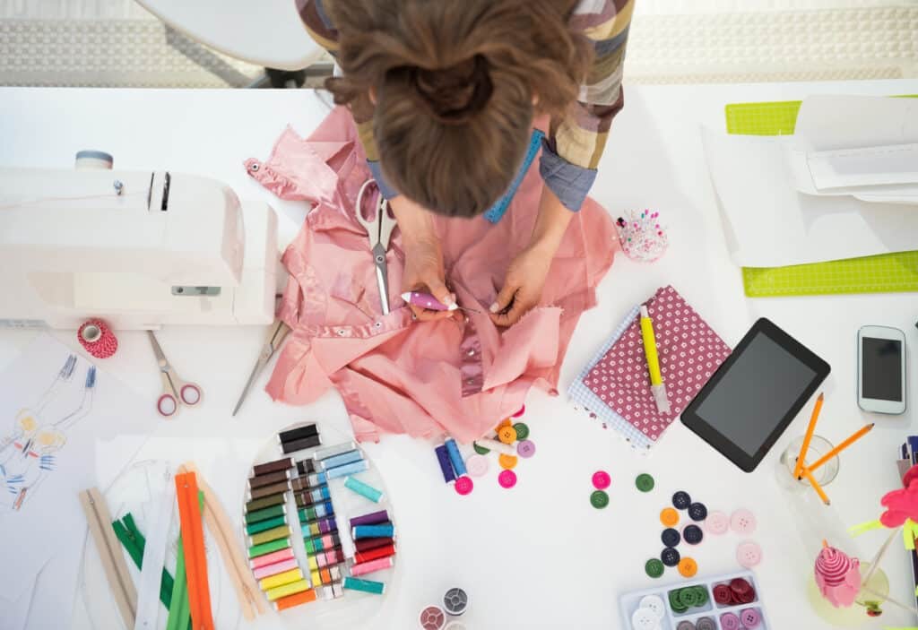 Seamstress working in her home studio, having her materials spread around her